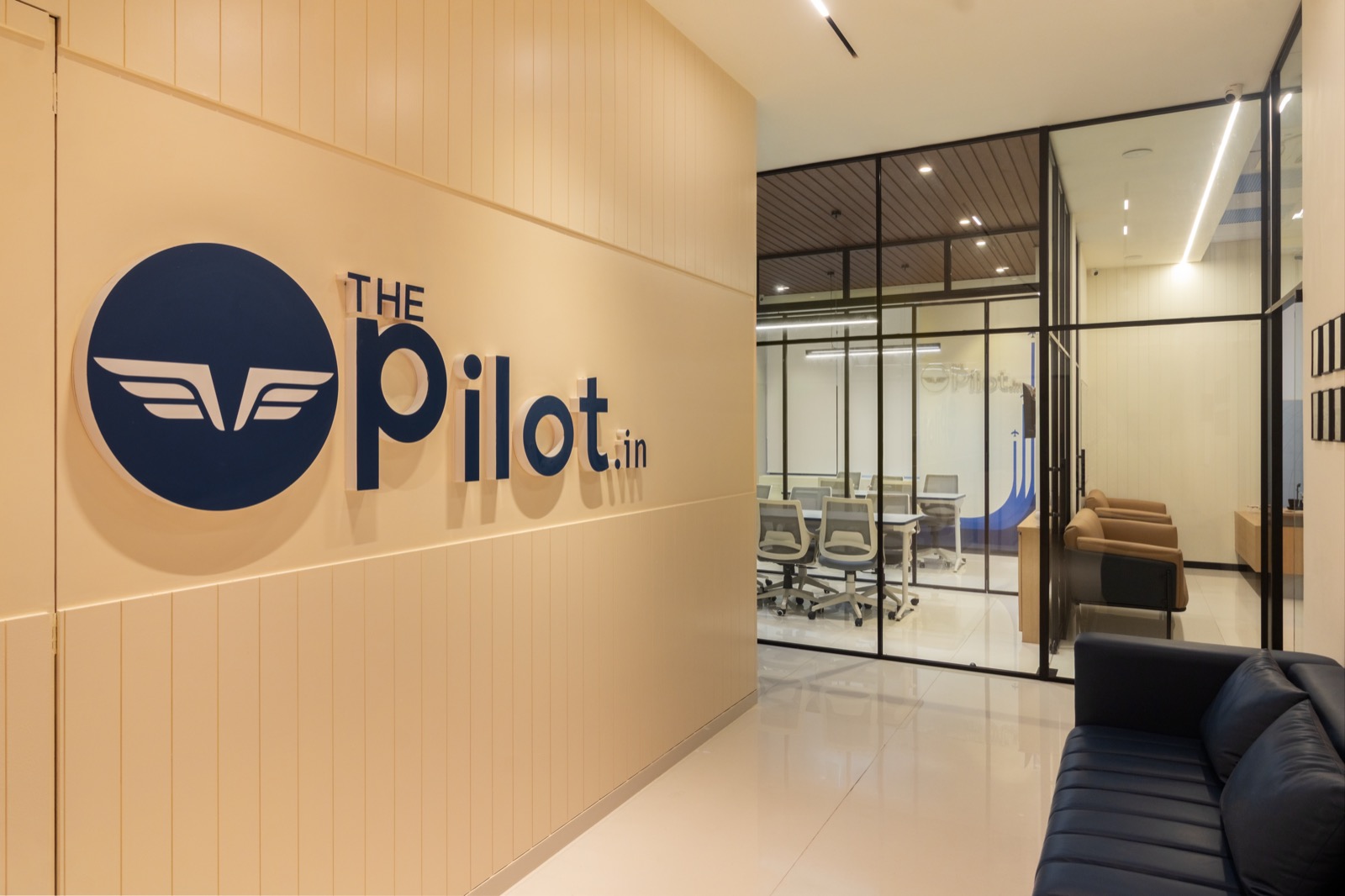 ThePilot.in office reception with brand logo wall and glass-walled meeting rooms