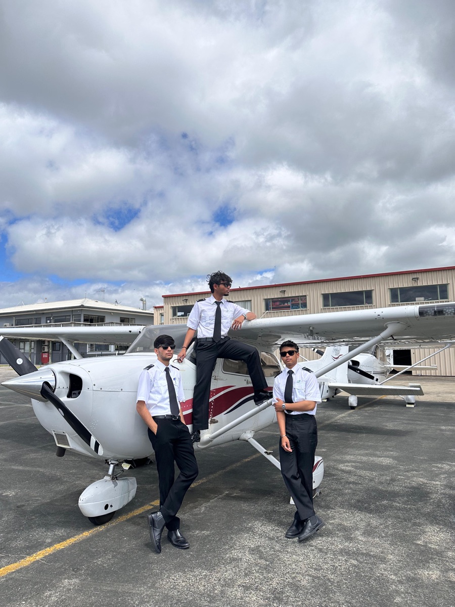 Three ThePilot.in cadets in pilot uniform posing beside a Cessna trainer aircraft
