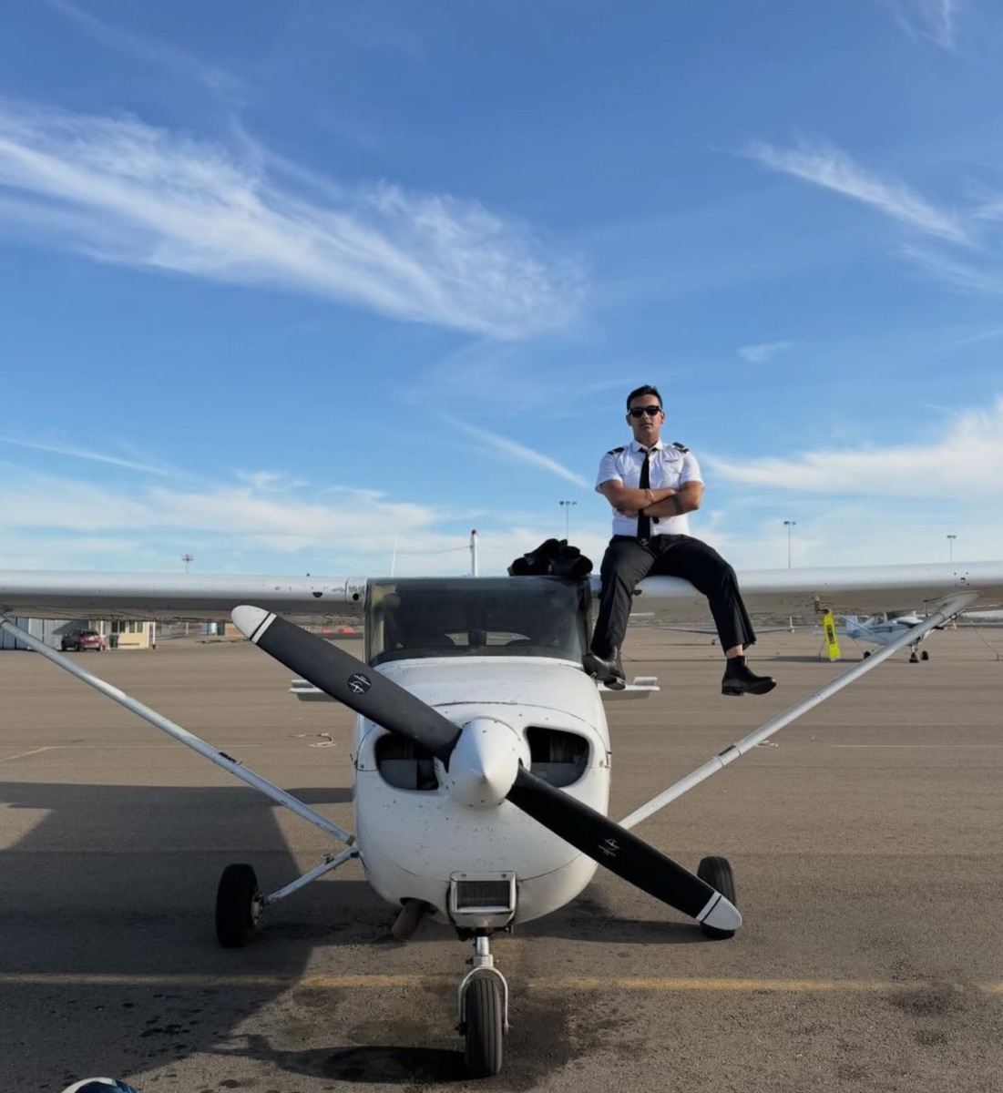 ThePilot.in student pilot in uniform seated on a Cessna trainer wing at an FTO tarmac